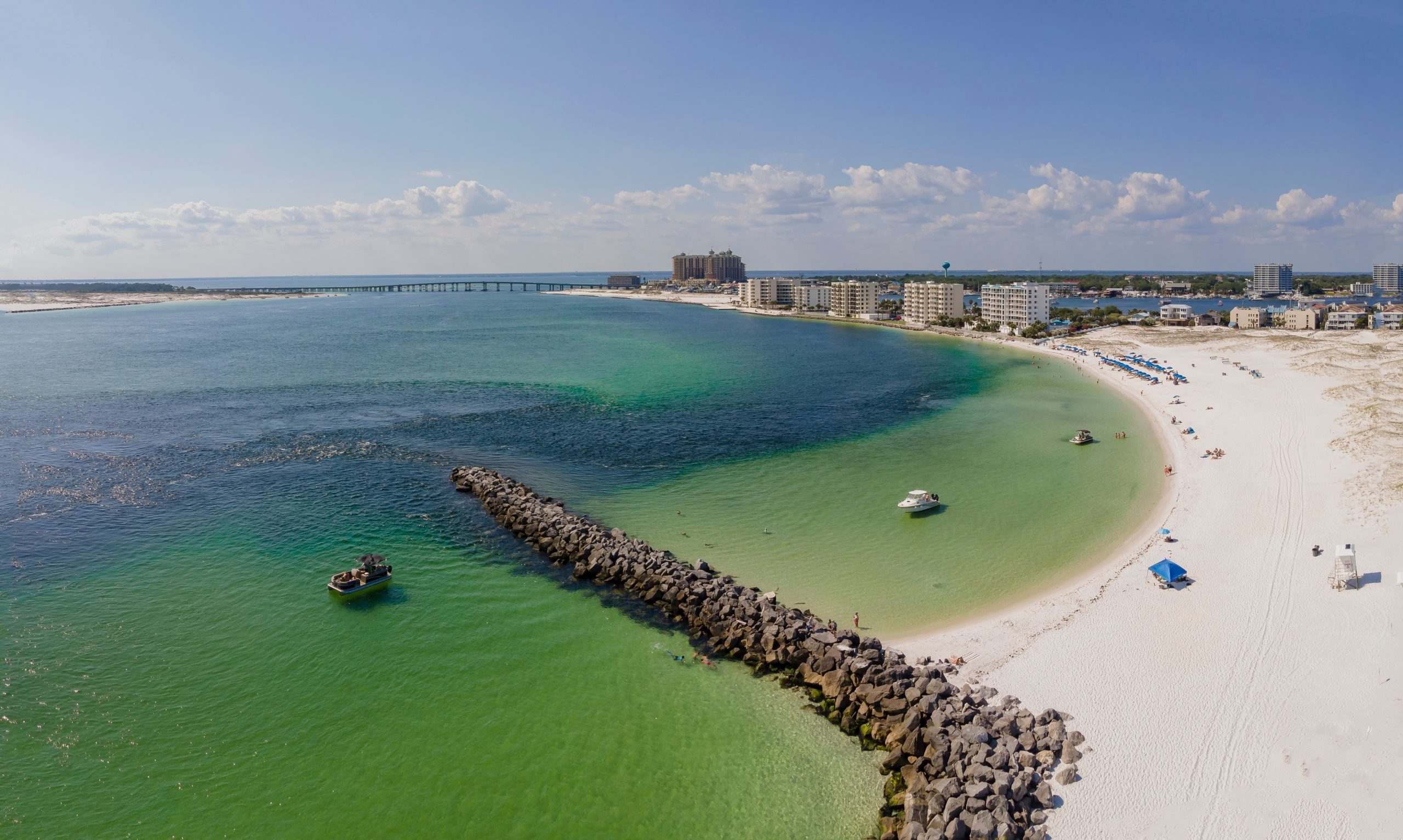 East,Jetty,In,Destin,Florida,With,Buildings,And,Clouds in Sky